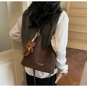 Detailansicht der braunen Hobo-Tasche aus PU-Leder mit Bärenanhänger und Markenlogo