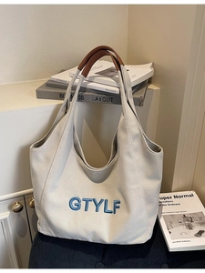Minimalist canvas tote bag with brown leather handles and blue letter embroidery