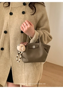Detail of dark brown lychee leather handbag with cute plush puppy charm accessory