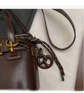 Detail of dark brown leather bucket bag with retro gold abacus pendant and woven knot