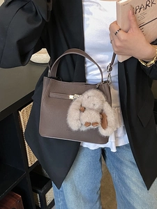 Vintage brown leather bucket bag with plush bunny charm for casual crossbody style