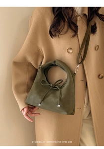 Close-up of olive green crossbody bag with a retro bow and silver hardware detail