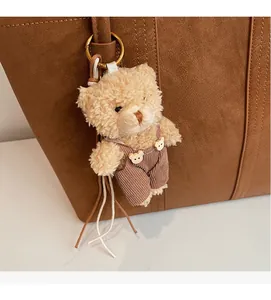Dettaglio di un portachiavi a forma di orsetto di peluche su una borsa in pelle marrone