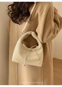 Detail of a beige leather tote with litchi texture and unique knotted handle design
