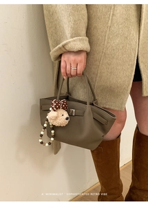 Detail of dark olive green leather bucket bag with cute bear and beaded charms