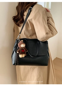 Dettaglio della borsa tote in pelle nera con ciondolo a forma di orso e tracolla regolabile