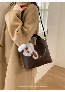 Detail view of deep brown leather bucket bag with a cute white bunny plush accessory