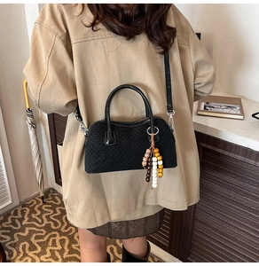 Détail du sac bandoulière tissé noir avec gland de perles colorées et boucle