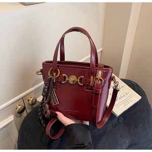 Detail of red leather bucket bag featuring a heart-shaped metal buckle and premium texture