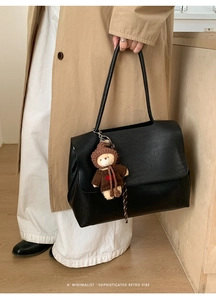 Dettaglio della borsa nera in pelle testurizzata con ciondolo a forma di orsetto bruno