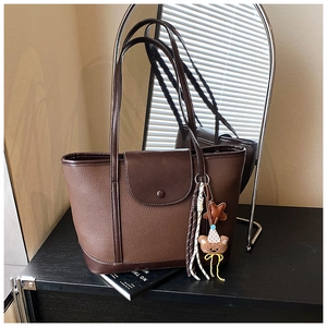 Detail view of large brown textured tote bag with cute bear charm and side mirror reflection
