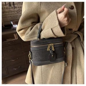 Detail of dark grey crocodile pattern handbag with white stitching and gold hardware