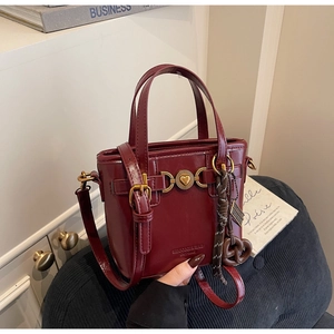 Close-up of dark red leather bucket bag with golden heart buckle and metal accents