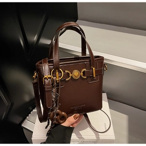 Detail of vintage brown bucket bag featuring a metal heart clasp and biscuit-shaped charm