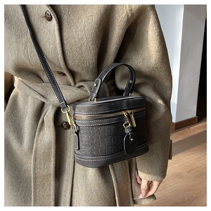 Charcoal grey bucket bag with crocodile texture worn with a camel wool coat on a model