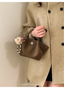 Close-up of retro dark brown litchi pattern bucket bag with silver lock and plush bear charm