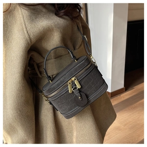 Detail of grey crocodile texture bucket bag with gold hardware and white stitching
