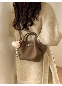 Detail of dark brown leather bucket bag with silver clasp and plush dog charm