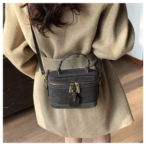 Detail of dark grey crocodile pattern bucket bag with retro gold hardware and contrast stitching