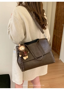 Dettaglio di una grande borsa tote retrò in pelle marrone caffè con patta e ciondolo