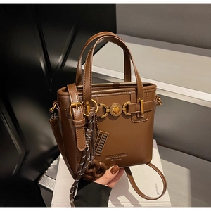 Detail of vintage brown leather handbag featuring gold horsebit heart hardware and charms