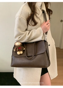 Dettaglio di una borsa tote marrone capiente con tracolla e un simpatico orsetto appeso