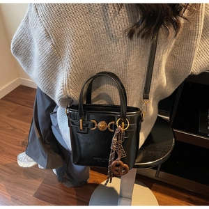 Detail of vintage heart buckle and woven rope charm on a black leather bucket bag