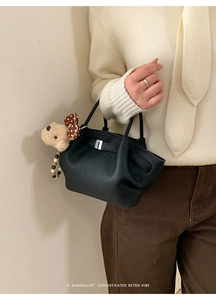 Close-up of black litchi pattern bucket bag with a cute puppy plush charm detail