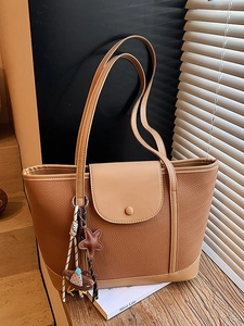 Brown litchi grain tote bag with bear charm and long shoulder strap in soft light