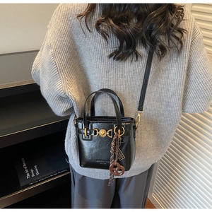 Detailed view of the black leather bucket bag with golden heart buckle and charms