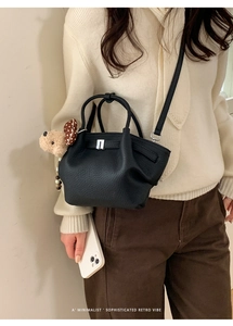 Detail of black lychee grain leather bucket bag with silver buckle and bear charm decor