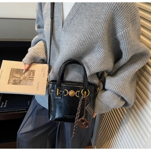 Detail of black glossy bucket bag featuring gold hardware and heart-shaped relief details