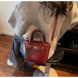 Detailed macro view of the vintage burgundy leather bag with a golden heart-shaped clasp