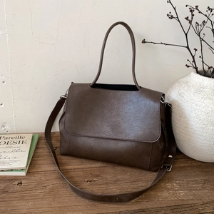 Dettaglio della borsa tote in pelle cerata marrone scuro con trama vintage naturale e tracolla