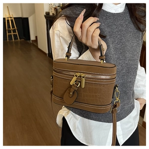 Detail of brown crocodile pattern bucket bag with double zippers and gold hardware