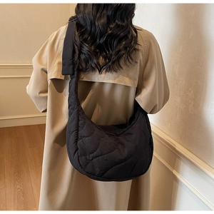 Close-up of black quilted half-moon crossbody bag with wavy stitching texture details