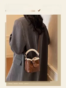 Détail d'un mini sac seau en cuir marron avec bordure en fourrure blanche et boucle métal