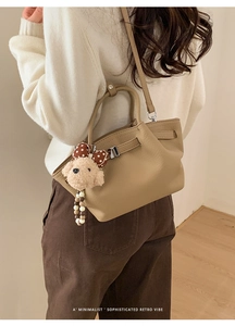 Detail of khaki bucket bag with textured leather and a cute plush puppy charm