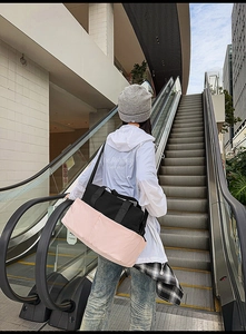 Dettaglio della borsa tote rosa e nera con tasche esterne su una scala mobile