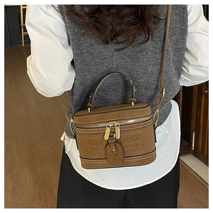 Brown crocodile-embossed bucket bag shown on model with white stitching details