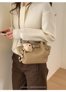 Close-up of khaki lychee textured leather bucket bag with cute teddy bear charm