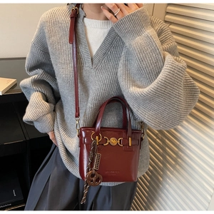 Detail of burgundy bucket bag with golden heart lock and decorative silk scarf charm