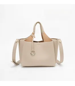 Detailed macro view of beige lychee texture leather handbag with metal ring pendant