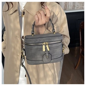 Detail of grey bucket bag showing the golden zipper and textured faux leather material