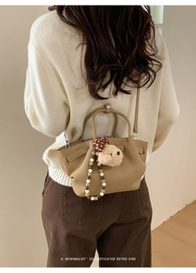 Detail of khaki pleated leather bucket bag with plush rabbit charm and beaded decor