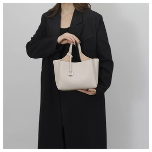 Detail of off-white bucket bag featuring lychee grain leather and metal ring pendant
