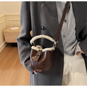 Détail du sac seau en cuir marron avec bordure en fourrure blanche et bandoulière réglable