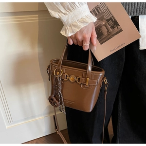 Detail of vintage brown PU leather bucket bag with gold heart clasp and strap