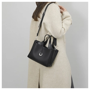 Close-up of black lychee grain leather tote bag worn with a beige cashmere coat
