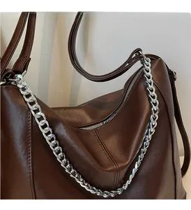 Detail of dark brown faux leather bag with thick silver metal chain and zipper